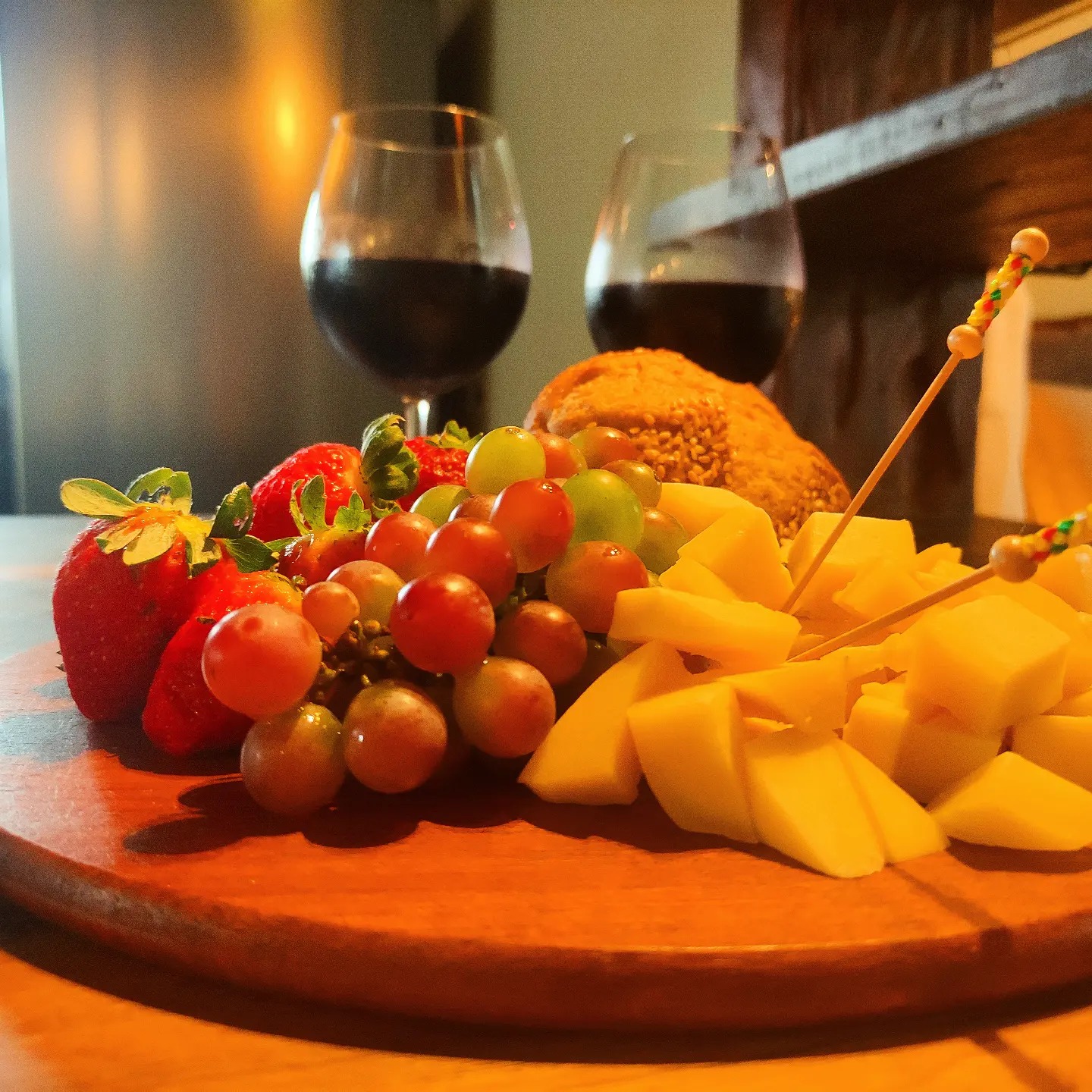 Tábua de frutas e queijos com taças de vinho na cabana